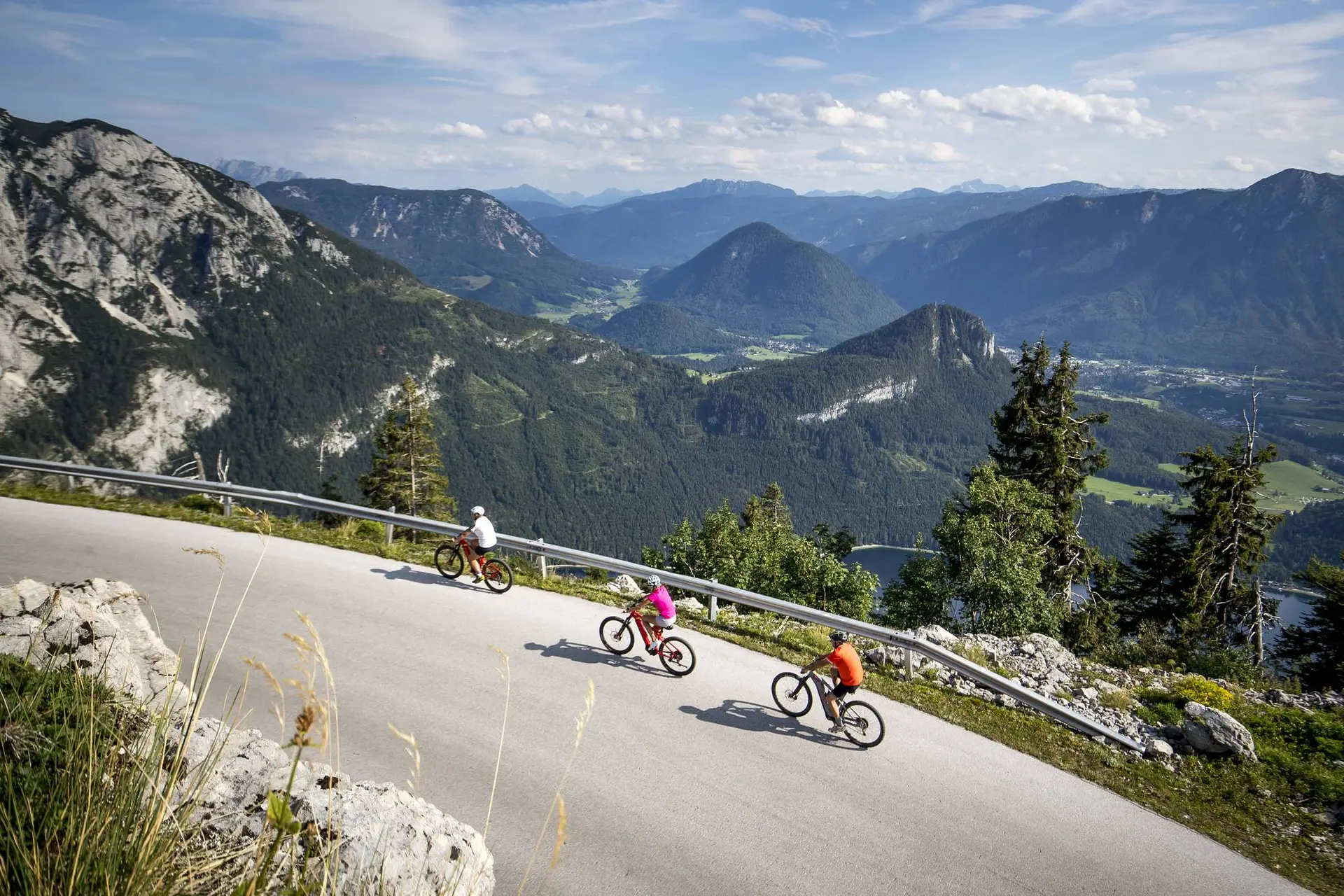 Drei Fahrradfahrer radeln sportlich die Loser Panoramastrasse bergauf.